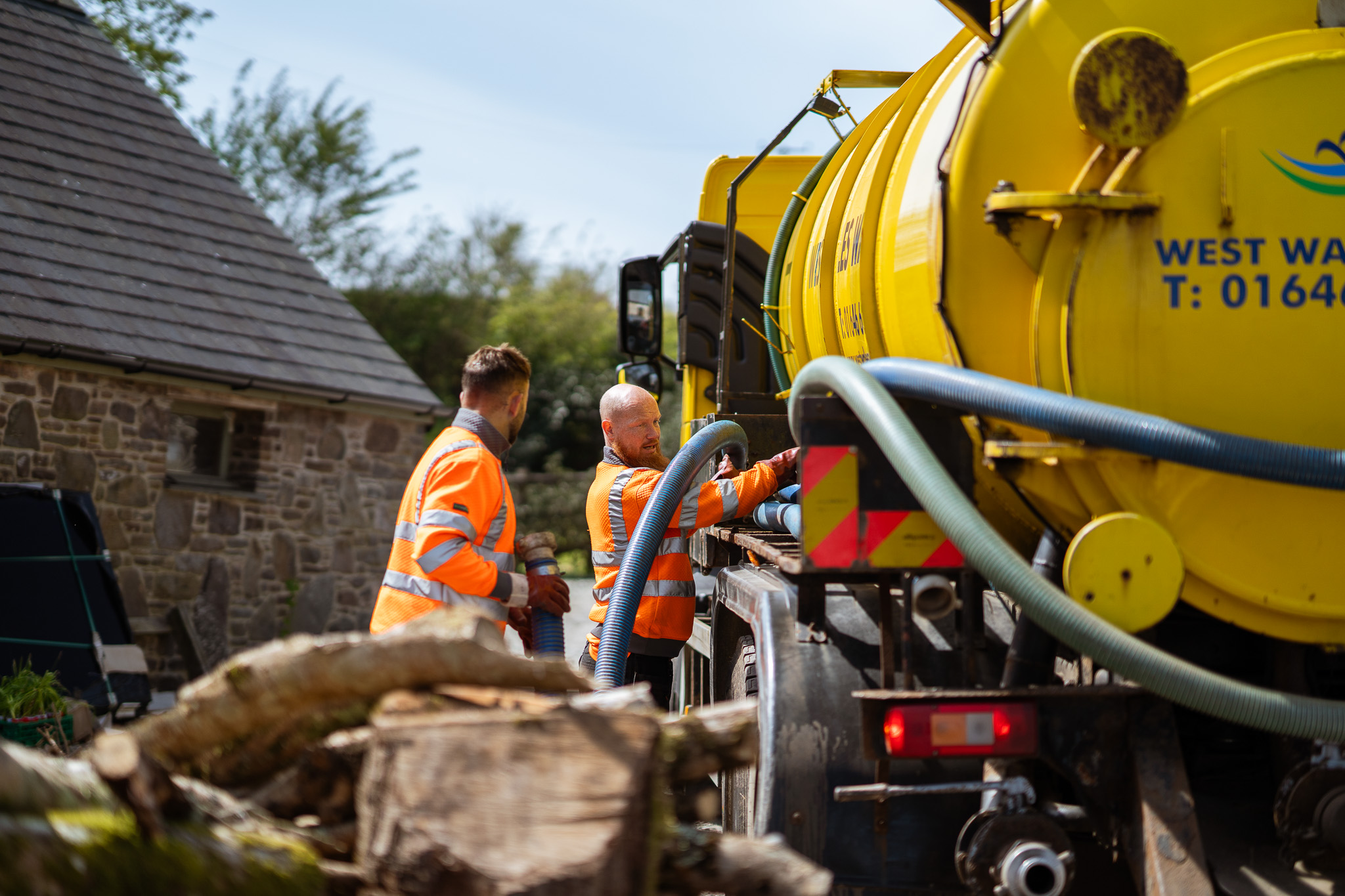 West Wales Waste operative moving extraction pipe by tanker at farm in Nolton Haven, Pembrokeshire - alternative view